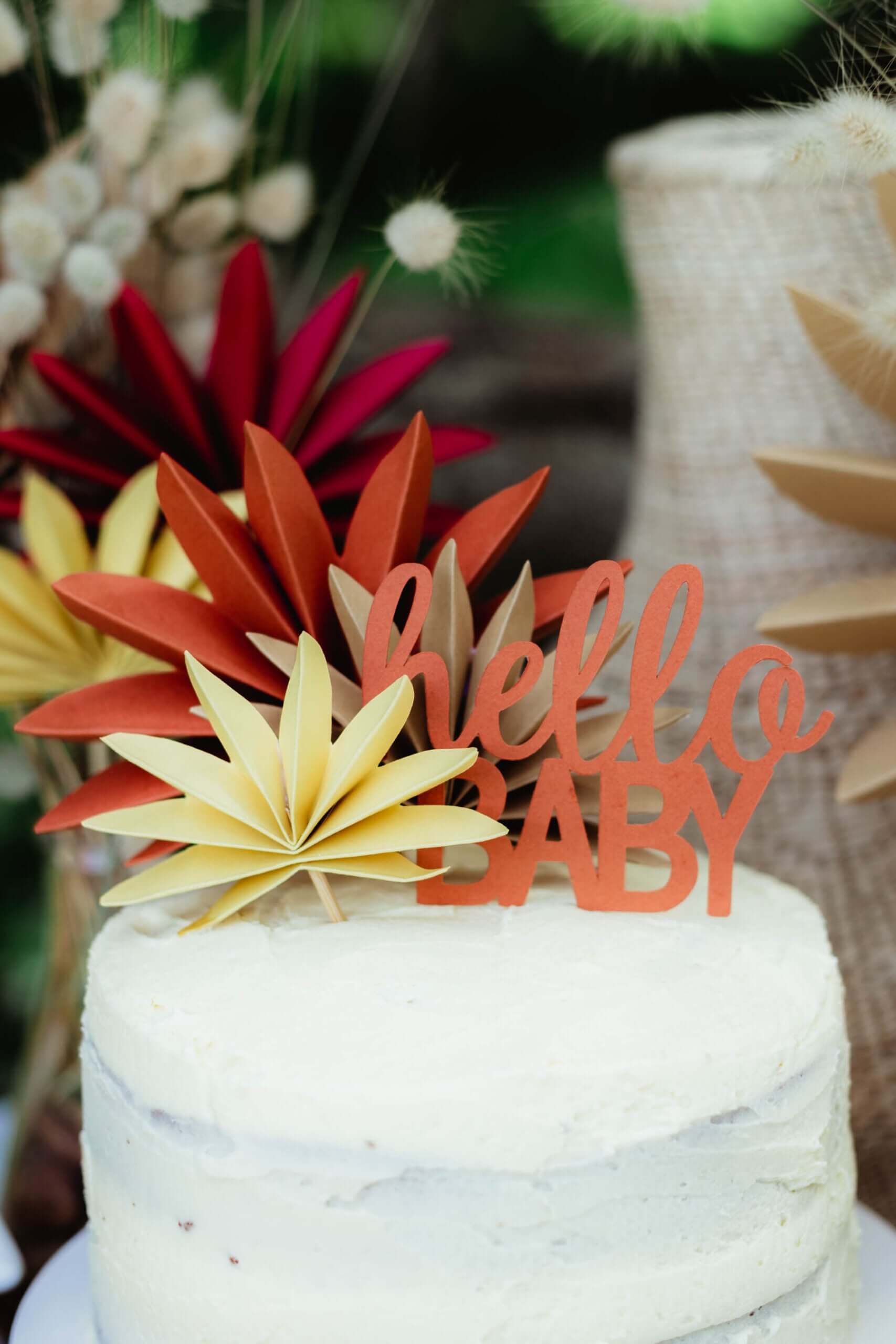 Hello Baby Cake Topper | Boho Baby Shower Decor (DIY) on a white cake with colorful paper flowers.